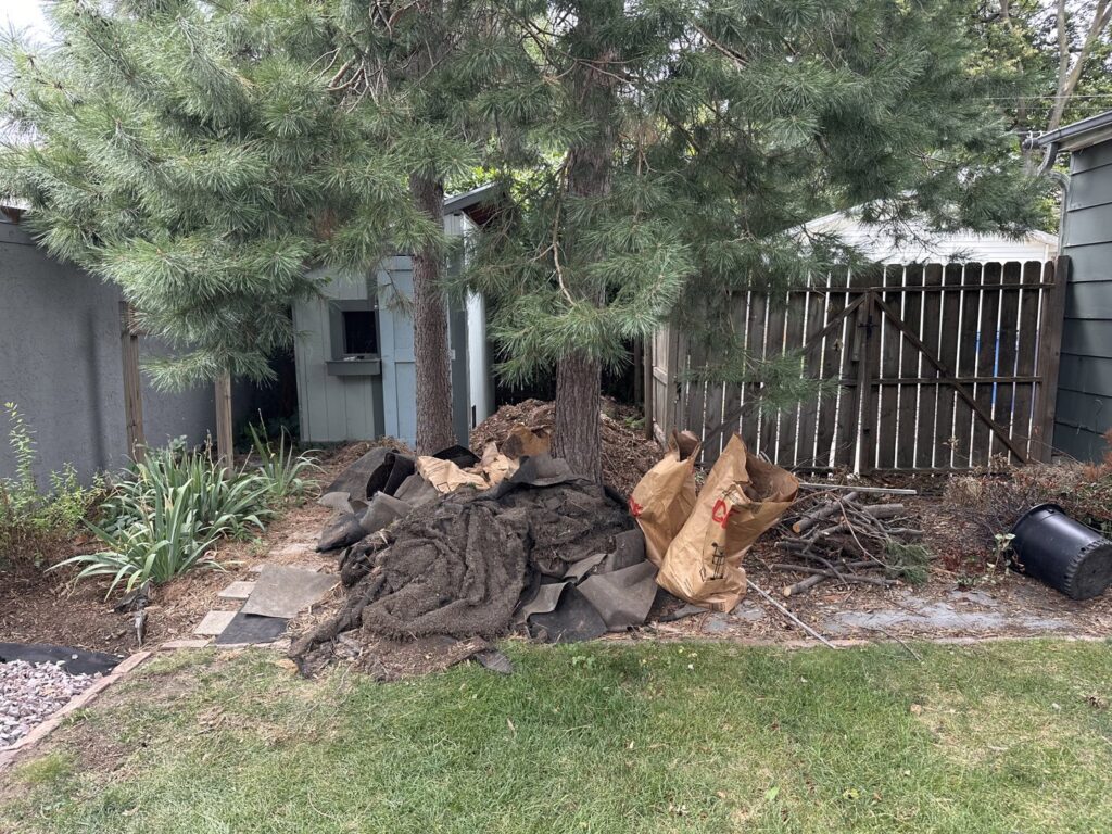 A large pile of landscaping debris and yard waste in a backyard, ready for BeeBop's Junk Removal in Sioux Falls, SD.