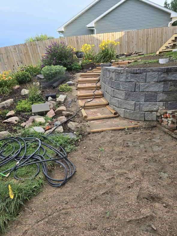 Landscaping project with a newly built retaining wall and brick steps by PRO HANDY FIXER in Kearney, NE.