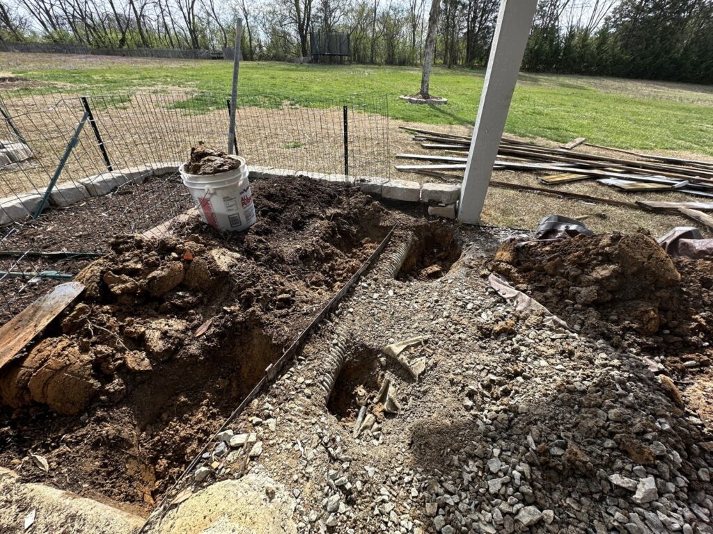 Landscaping site preparation with moved dirt and a white bucket by Rainscapes in Louisville, TN.