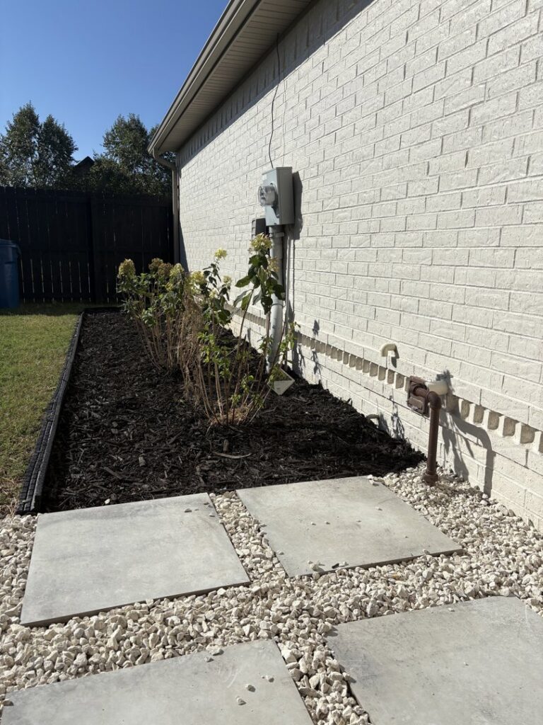 Fresh landscaping featuring dark mulch, plants, and concrete stepping stones installed by HomeFront Services LLC in Fayetteville, AR