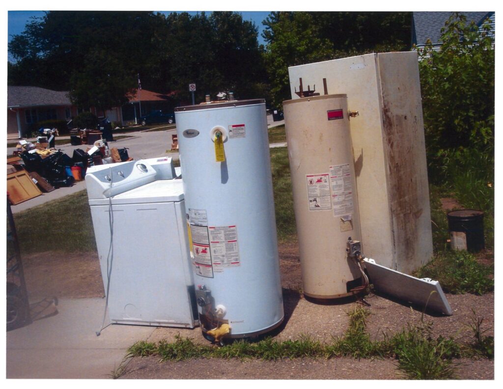 Large appliances including water heaters and a washing machine awaiting removal by Kaveman Hauling LLC in Ankeny, IA.