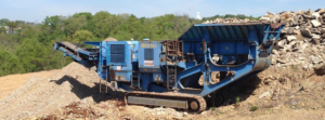 A large blue crushing machine processing demolition debris on a job site by Massarelli Excavating & Demolition in Pittsburgh, PA.