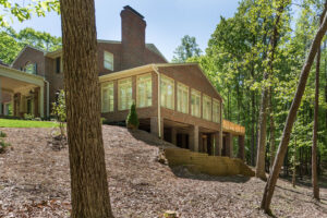 A large brick house featuring a sunroom addition and a wooded backyard, showcasing construction work by Paradise Found Construction in Cary, NC.