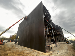 A large building under construction with dark architectural precast panels being installed by Lombard Architectural Precast Products Company in Aurora, IL.
