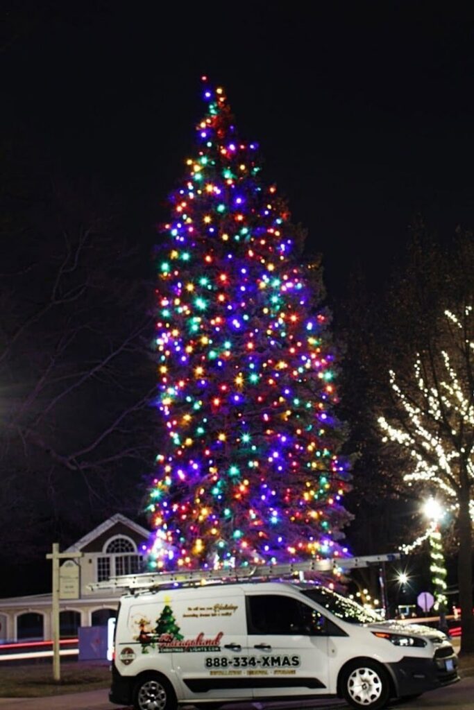 A large, brightly lit Christmas tree with a service van from Chicago Christmas Lights LLC parked nearby in Chicago, IL.