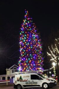 A large, brightly lit Christmas tree with a service van from Chicago Christmas Lights LLC parked nearby in Chicago, IL.