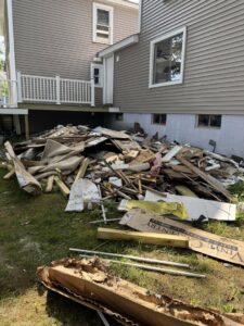 A large pile of construction and demolition debris next to a house, ready for removal by Junk Removal Brothers in Worcester, MA.