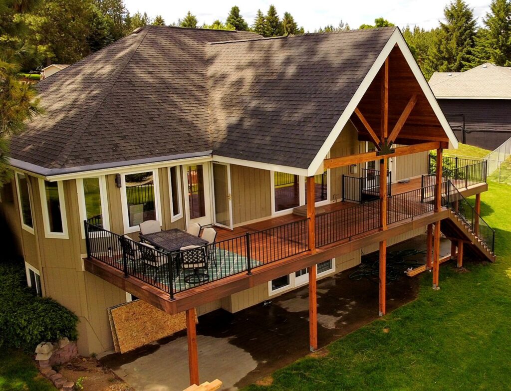 A large, elegant composite deck featuring a covered section and sturdy railing, expertly built by Ridgeline Decks in Spokane, WA.