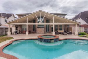 A large house with an extensive covered patio, swimming pool, and spa by Houston Home Improvements & Construction in Houston, TX