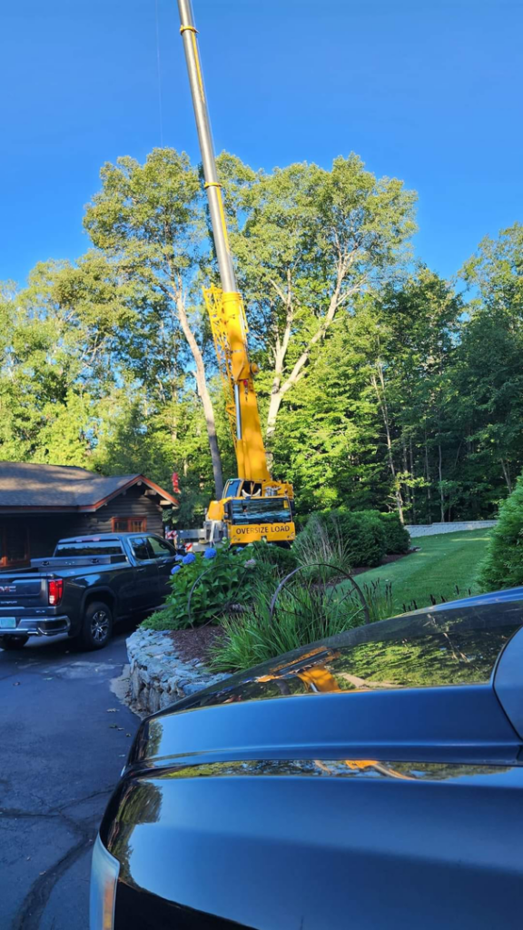 A large yellow crane extended for professional tree removal service by Out On A Limb Tree Service in Lowell, MA.