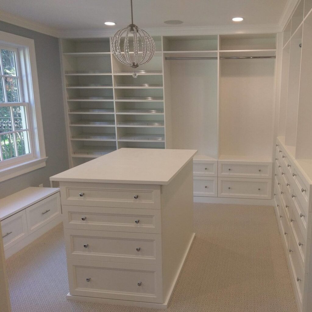 A spacious custom walk-in closet with an elegant central island installed by Closet Creations Inc. in Sleepy Hollow, NY.