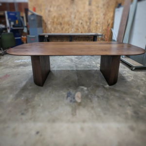 A large custom-made wooden conference table crafted by Gilbert Designs Tulsa, OK, in a workshop setting.