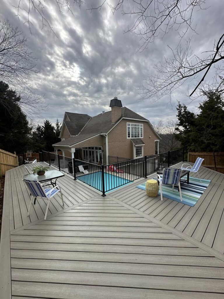 A large deck surrounding a swimming pool with safety fencing, constructed by Deckscape KC in Kansas City, MO.