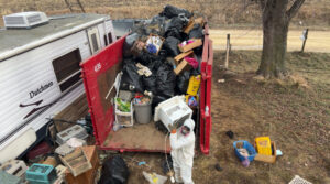 A large red dumpster filled with black trash bags and various junk, handled by Rosales Junk Removal in Des Moines, IA.