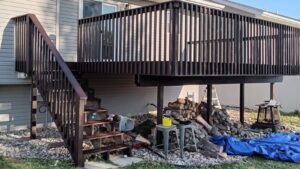 A large elevated wooden deck with dark brown stain and stairs, a completed project by The Creative Carpenter in Minot, ND.