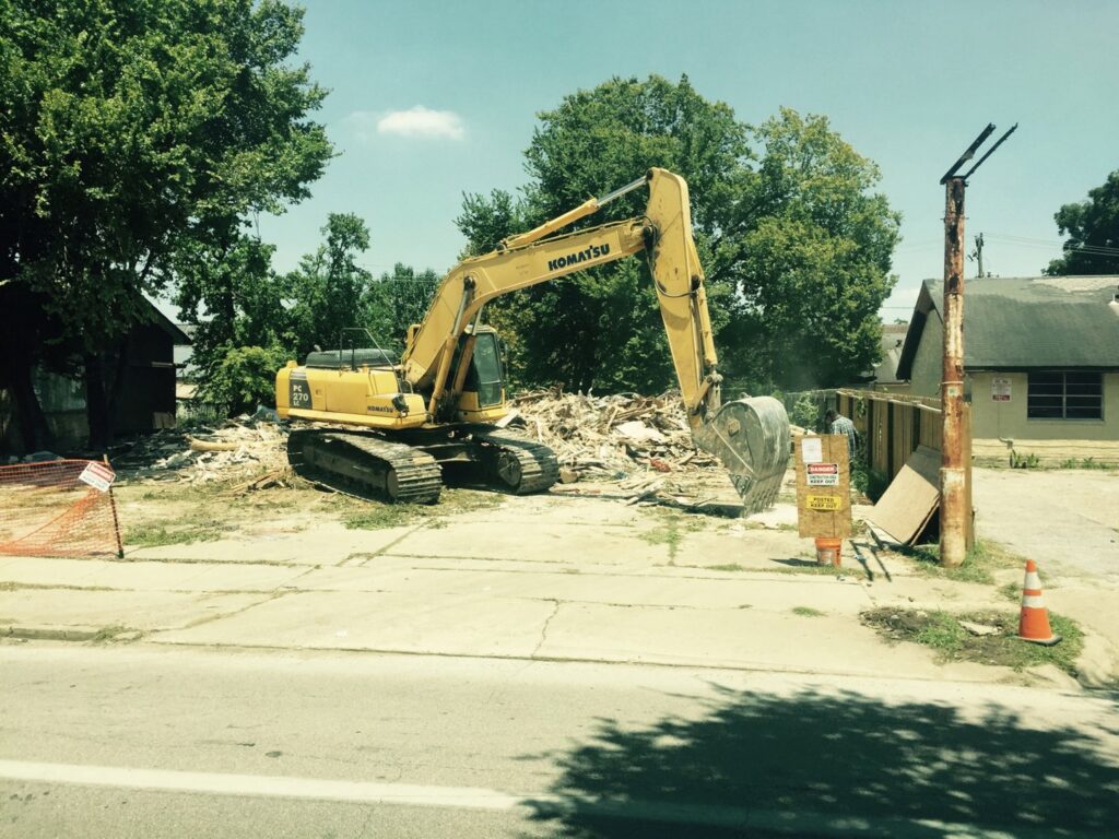 A large excavator working on a demolition site with piles of debris for All Aboard Contractors in Houston, TX.