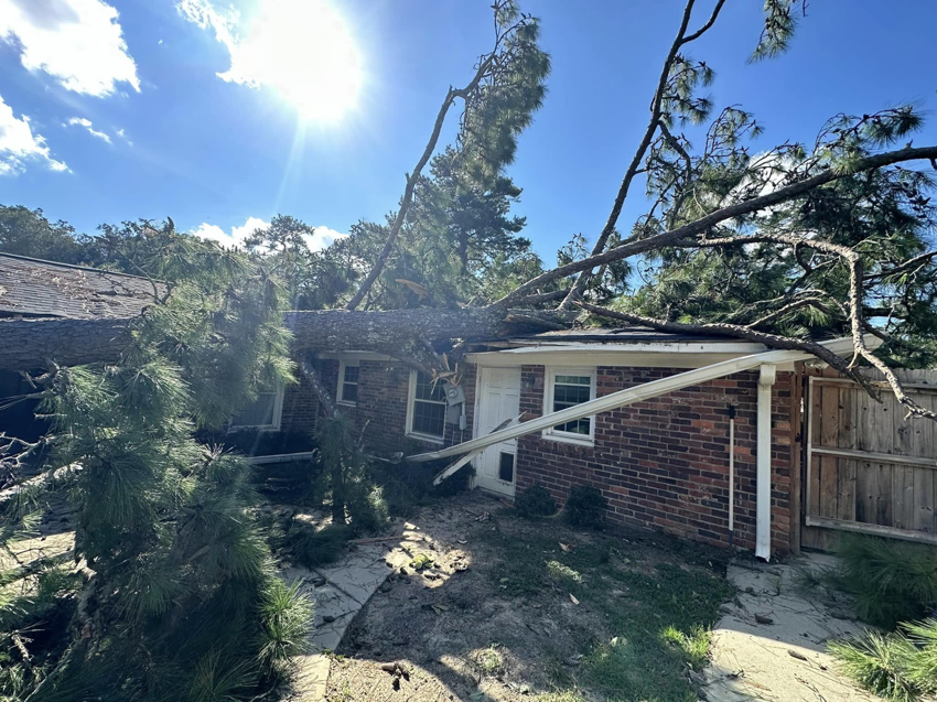 A large fallen tree causing extensive damage to a house, requiring storm cleanup services from GNC Tree Service, LLC in Columbia, SC.