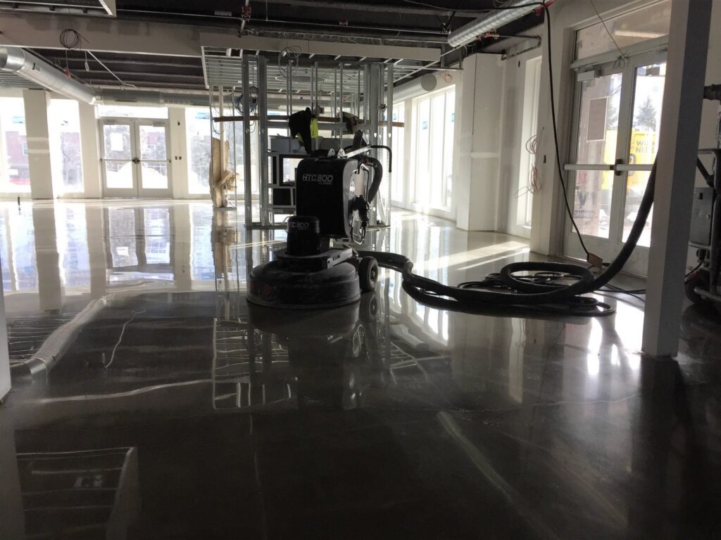 A large floor grinding machine in a commercial space under construction by Heavy Duty Floors, LLC in New Britain, CT.