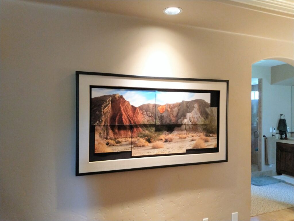 A large, framed panoramic artwork professionally mounted on a wall with a spotlight by Boise Handyman & Remodel in Boise, ID.