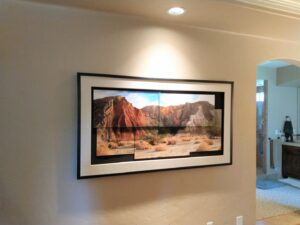 A large, framed panoramic artwork professionally mounted on a wall with a spotlight by Boise Handyman & Remodel in Boise, ID.
