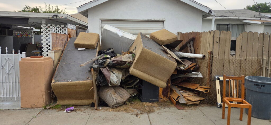 A large pile of old furniture and debris outside a house, ready for New Haul Junk Removal in Los Angeles, CA.