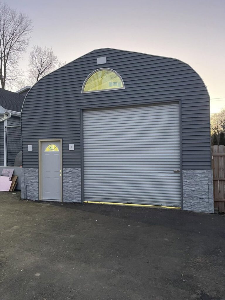 A newly constructed large garage with dark gray siding and a roll-up door by S-Squared Construction in Madison, WI.