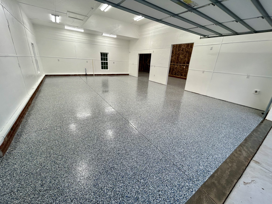 A spacious garage with a newly applied speckled floor coating by Garage Upgrade Pros in Fort Mill, SC.