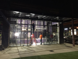 Workers installing large glass window panels on a commercial building by Recreated in Birmingham, AL.