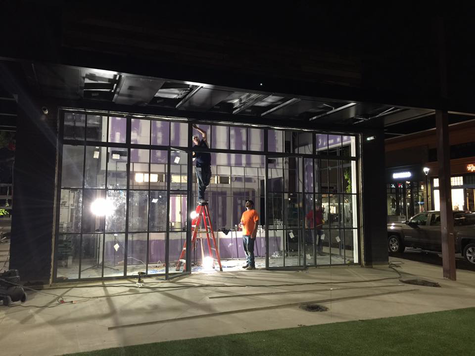 Workers installing large glass window panels on a commercial building by Recreated in Birmingham, AL.