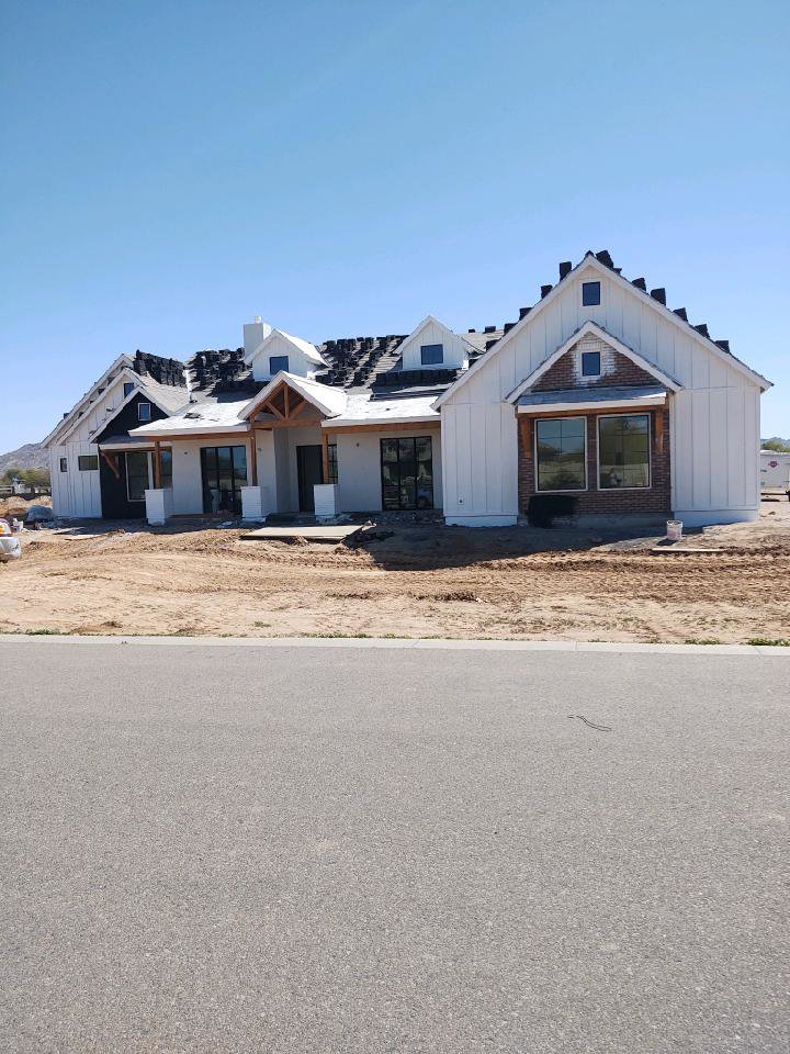 The exterior of a large house under construction with white siding and roof by AZ Framing and Remodeling in Peoria, AZ