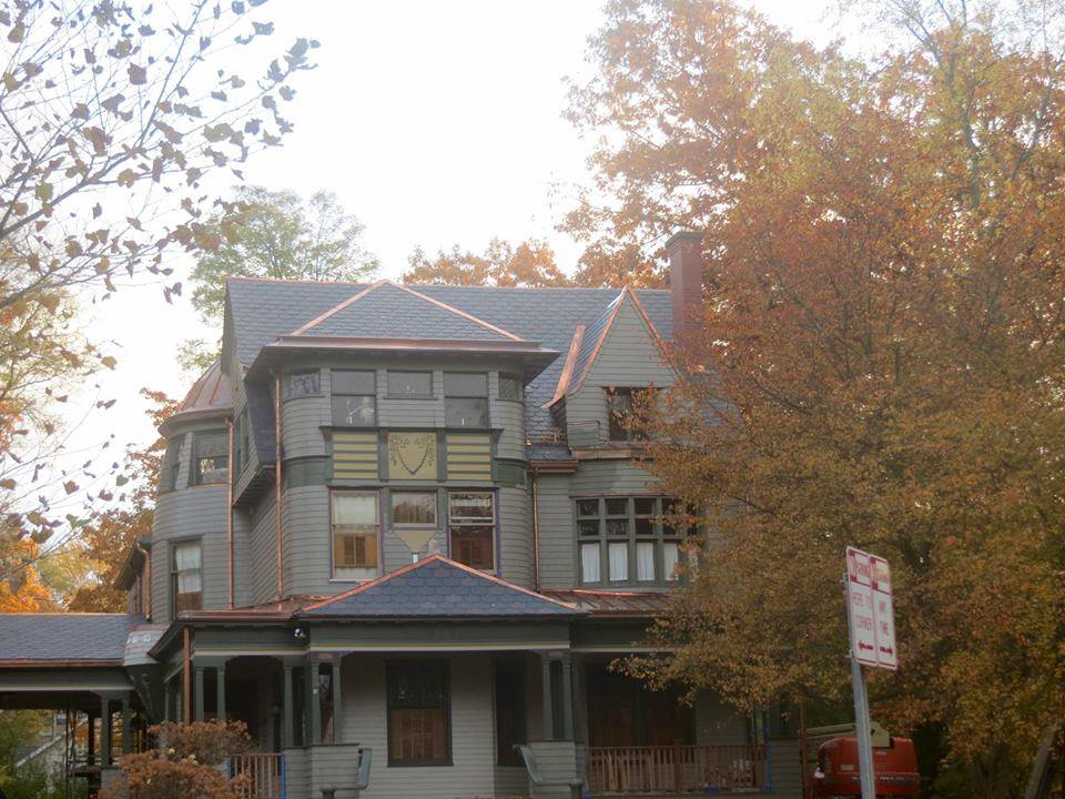 The exterior of a large house showcasing a new slate roof and copper accents by Copper & Slate Inc. in Buffalo, NY
