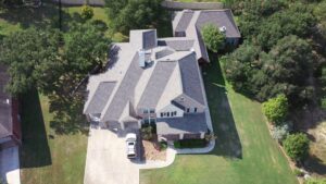 Aerial view of a large house with a newly installed shingle roof by PaRu Construction LLC in San Antonio, TX