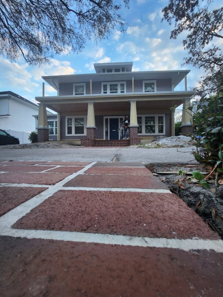 A large, newly renovated house with new siding, columns, and a welcoming porch, completed by Alejandro Melo Contractor corp in Tampa, FL.