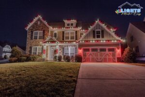 A large house decorated with festive red and white roofline lights by Lights Made Easy of Charleston, SC