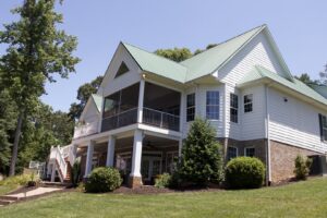 A large house with a newly constructed screened porch and a distinctive green metal roof by Screen Enc in Denver, NC
