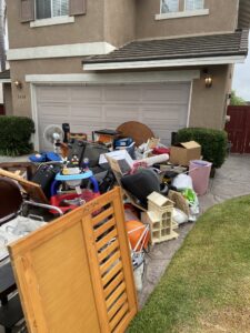 A large pile of household junk and debris awaiting removal from a driveway by Gabriel's Hauling & Junk Removal Services in San Diego, CA.