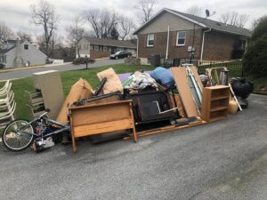 A large pile of household junk, furniture, and debris on a driveway ready for removal by Junk Lockdown LLC in Lancaster, PA.