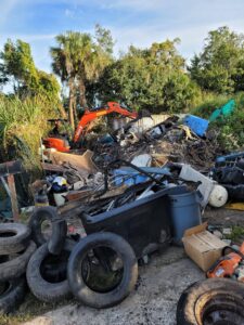 Large pile of mixed junk and debris being cleared with an excavator by Jugganott Recycling, LLC in Orlando, FL.