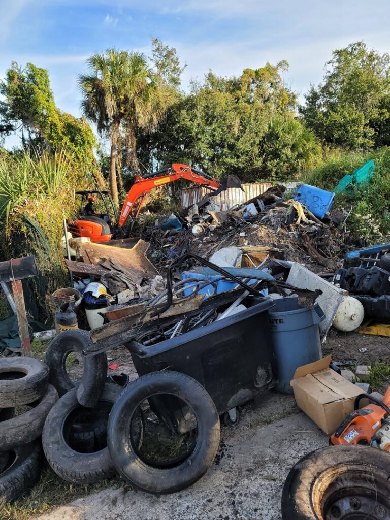Large pile of mixed junk and debris being cleared with an excavator by Jugganott Recycling, LLC in Orlando, FL.