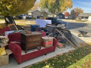 A large pile of household junk and debris on a residential driveway, ready for Junk Holler to remove in Boise, ID.