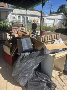 A large pile of various junk items with a smiling worker from Tiny Monster Junk Removal LLC in Denver, CO, on site.