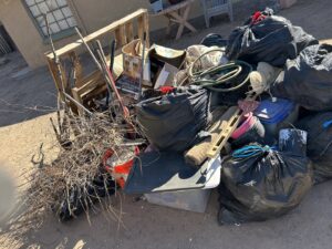 A large pile of mixed junk, including black trash bags, branches, and household items, ready for yard cleanup by Discount Hauling in Las Cruces, NM.