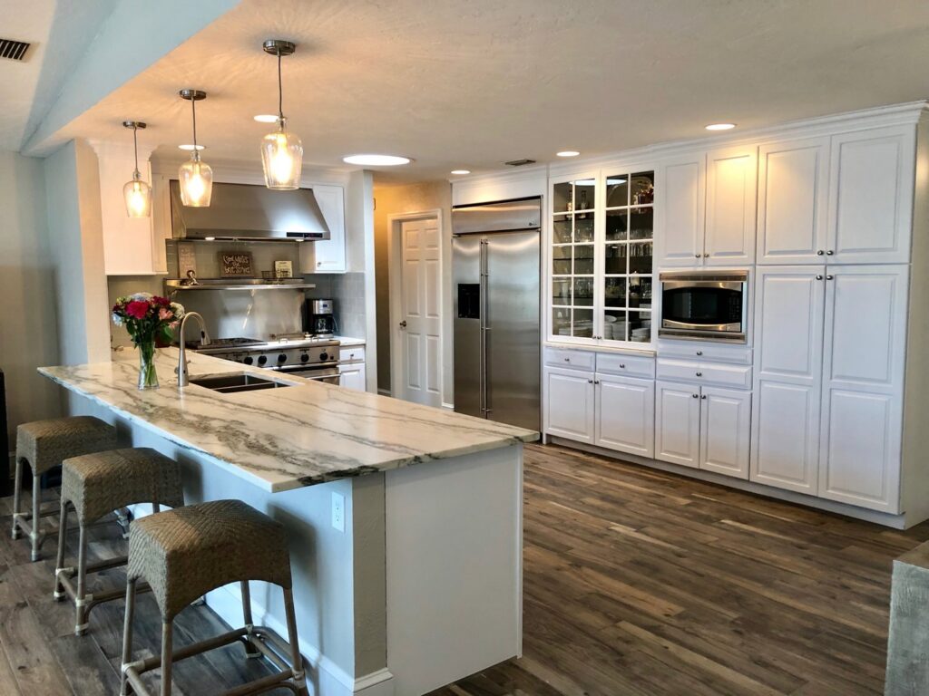 A spacious kitchen with white cabinets, a large marble island, and modern pendant lights, completed by Pioneer Built in St. Petersburg, FL.