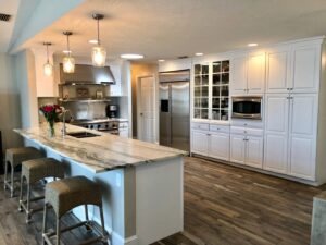 A spacious kitchen with white cabinets, a large marble island, and modern pendant lights, completed by Pioneer Built in St. Petersburg, FL.