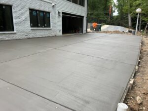 A large, newly poured concrete driveway or slab next to a residential garage by Rodriguez Concrete Creations in Rock Hill, SC.
