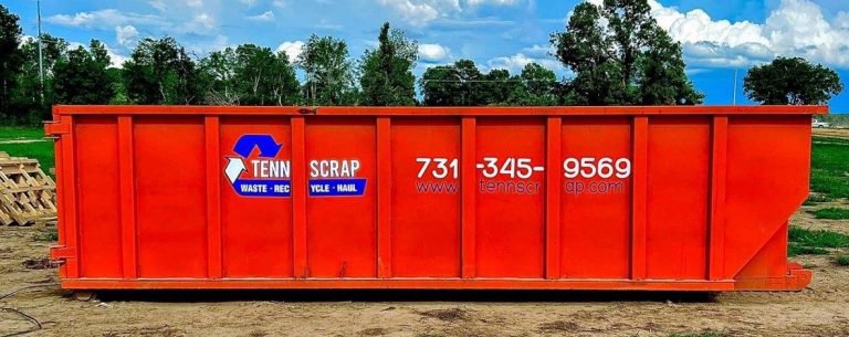 A large orange roll-off dumpster branded with Tenn-Scrap for waste hauling in Jackson, TN.