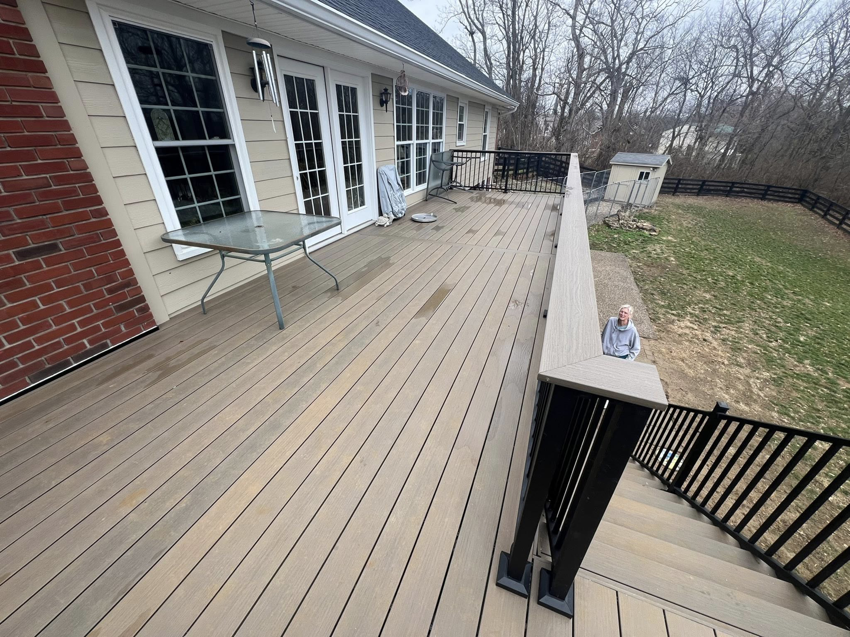 A large outdoor composite deck installation with black railing by Decks Unlimited, a handyman service in Littleton, CO.