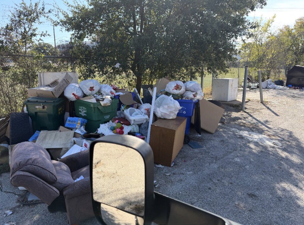 A large outdoor pile of various junk items, including trash bags and furniture, awaiting removal by Junk Out Boyz LLC in Georgetown, TX.