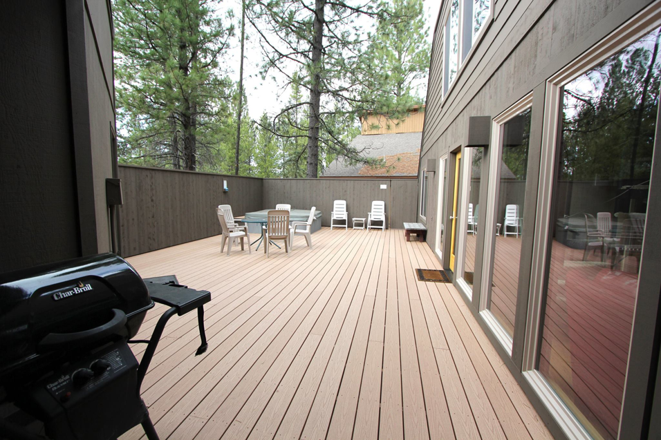 A spacious outdoor wooden deck with patio furniture and a grill by Winch Construction in Bend, OR.