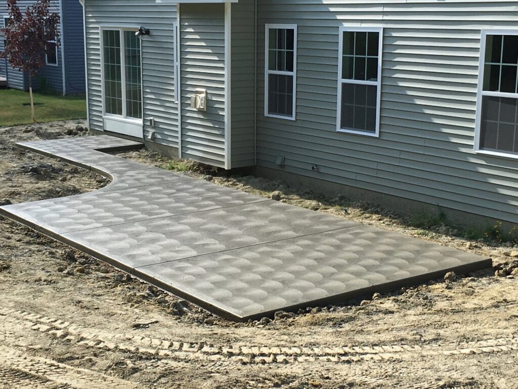 A large patterned concrete patio next to a house, recently completed by Paris Brothers & Company, Inc in Erie, PA